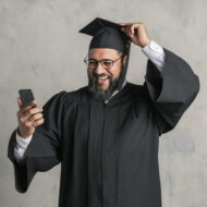 Senior man in a graduation gown using his mobile phone